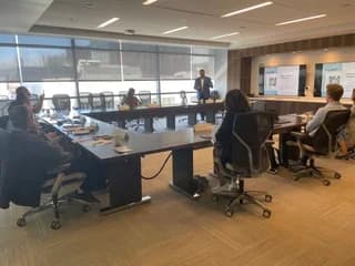Dr. Michael Njo participating in a boardroom-style meeting with dental leaders seated around a conference table.