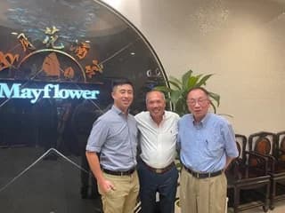 Dr. Michael Njo standing with two colleagues in front of a Mayflower sign.