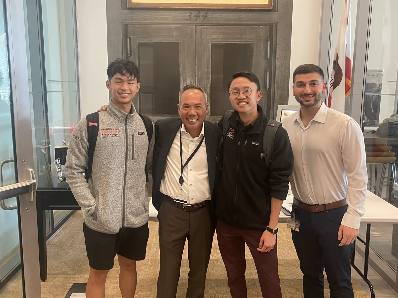 Dr. Michael Njo standing with three Dugoni Business Club student members inside the Arthur A. Dugoni School of Dentistry.