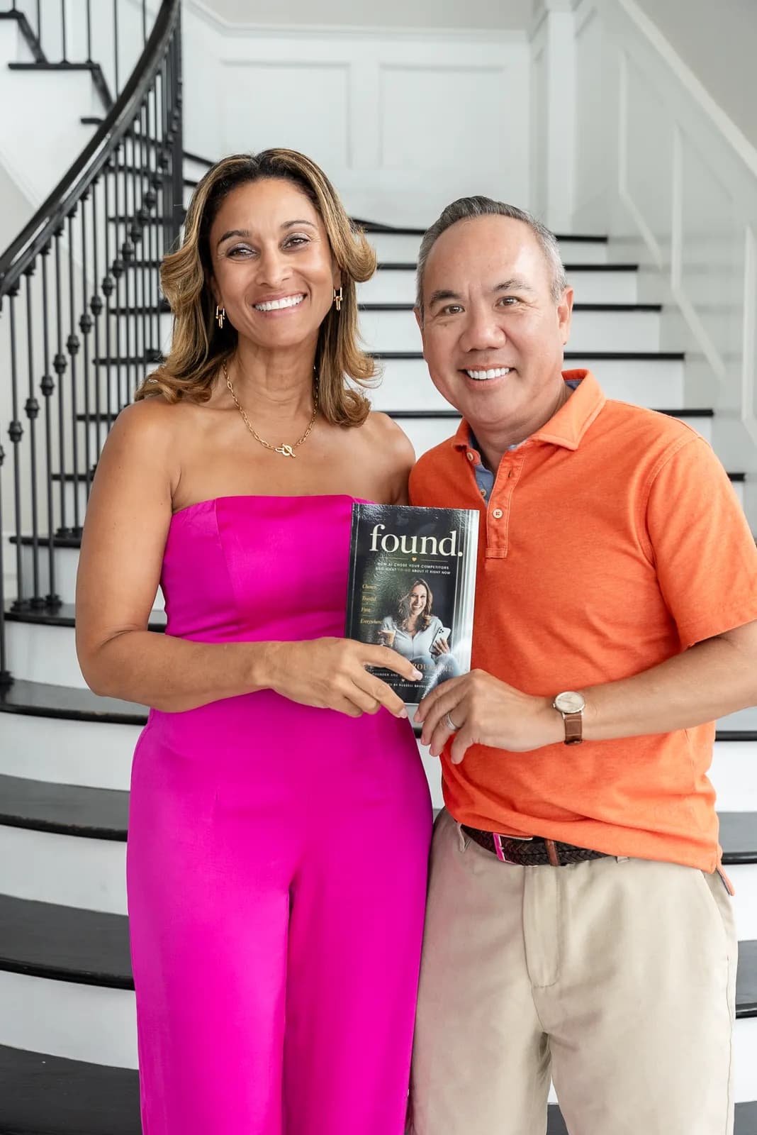 Dr. Michael Njo and Dr. Anissa Broussard holding a copy of her book FOUND on a staircase.