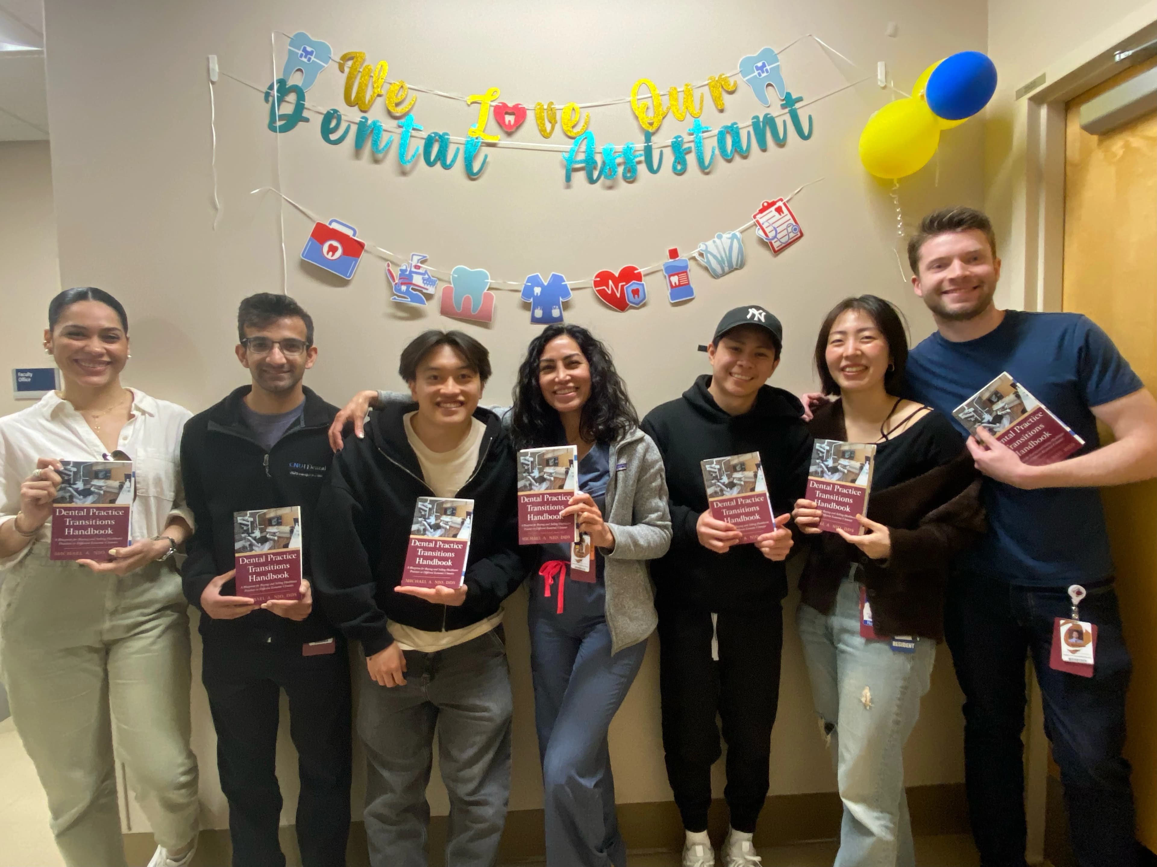 Dr. Michael Njo, DDS presenting to General Practice Residency residents holding copies of Dental Practice Transitions Handbook